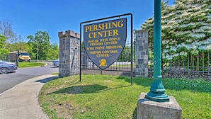 A sign for the Pershing Center with a stone building and a green fence in the background. - Updated Home w/ Patio Half Mile to West Point (Highland Falls)