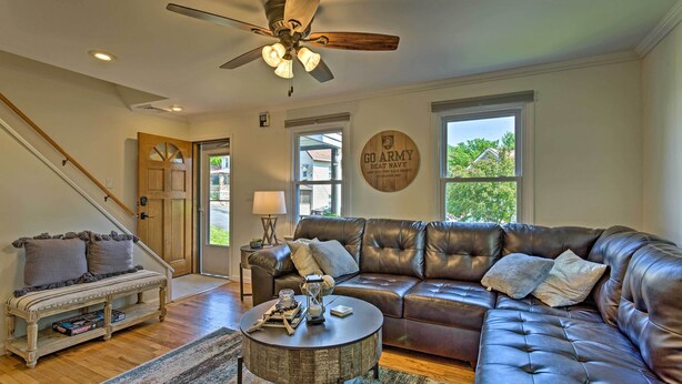 A living room with a leather sofa, a round coffee table, a bench, and a ceiling fan. - Updated Home w/ Patio Half Mile to West Point (Highland Falls)