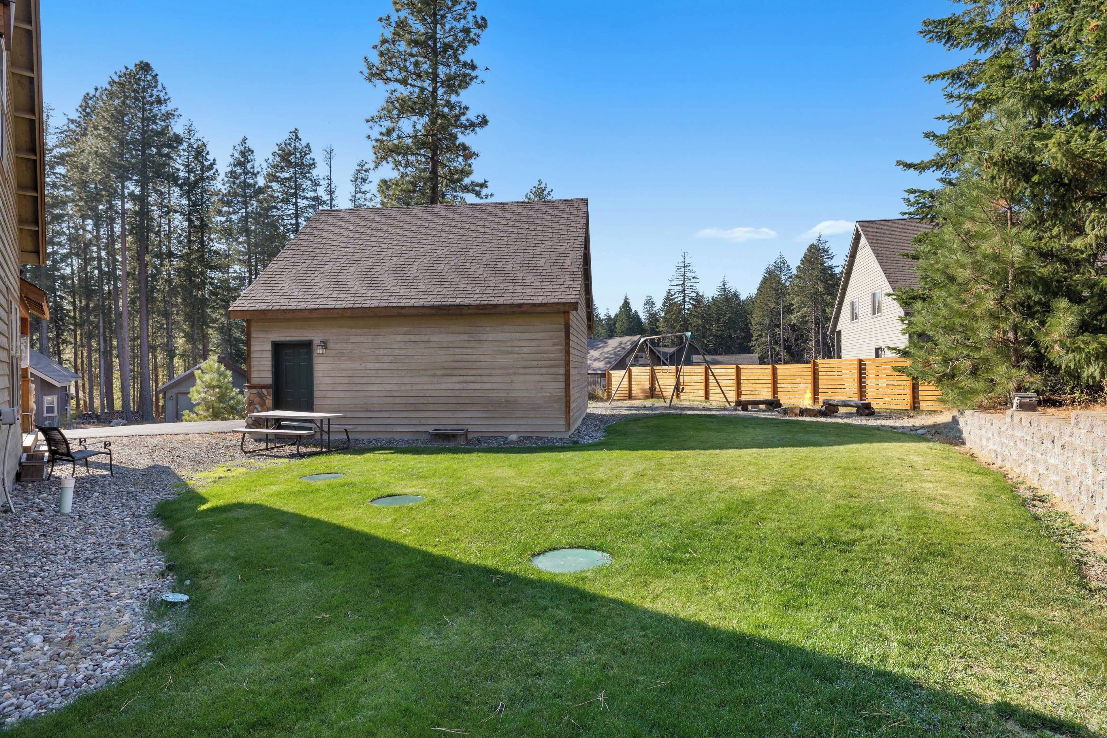 A wooden cabin with a sloped roof, a picnic table, and a stone wall.