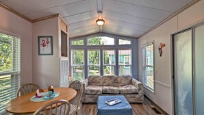 A cozy room with a wooden dining table, a cushioned sofa, and a small ottoman.