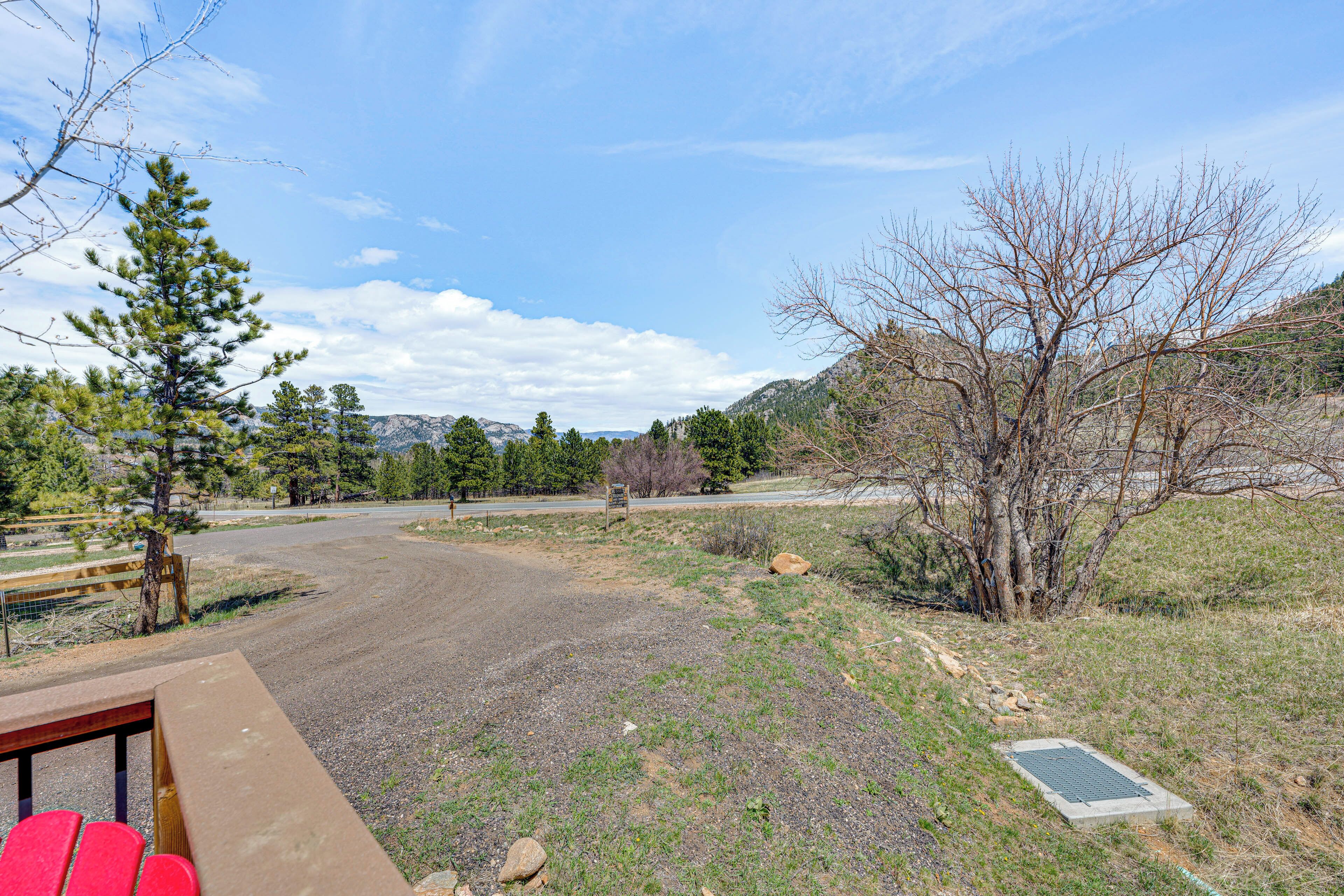 A gravel road leading to a parking area with a picnic table and red chairs.