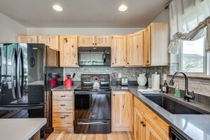 Una cucina moderna con mobili in legno, elettrodomestici in acciaio inossidabile e un'ampia finestra che offre luce naturale.