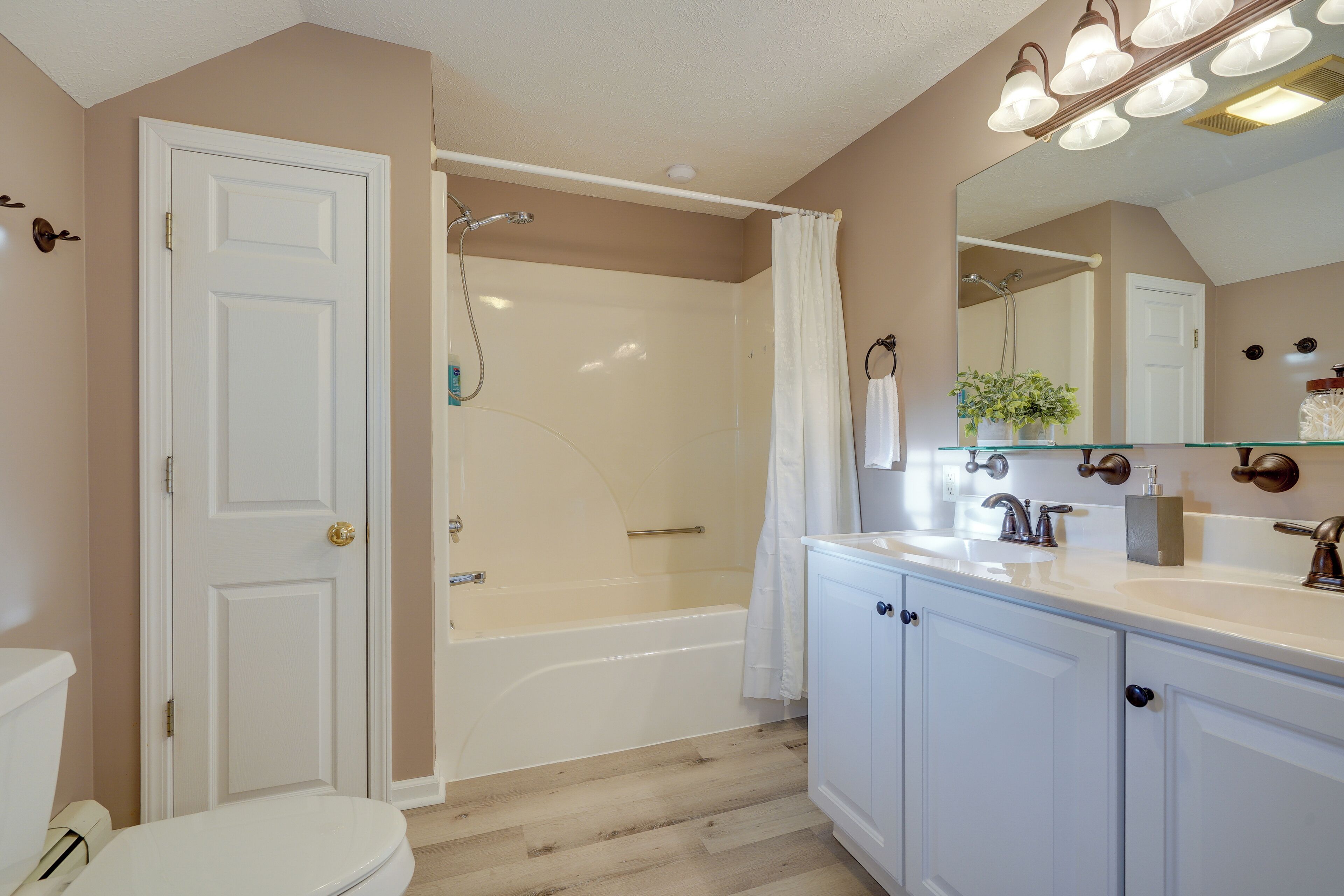 A bathroom with a bathtub, toilet, and vanity with a mirror.