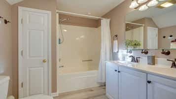 A bathroom with a bathtub, toilet, and vanity with a mirror.