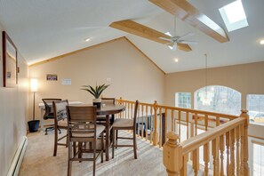 A dining area with a table and chairs, a ceiling fan, and a view of the outside through large windows. - Sauna, Spa & Stargazing: Coudersport Home! (Coudersport)