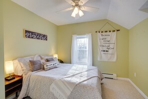 Une chambre à coucher comprenant un lit, des tables de chevet, un ventilateur de plafond, une fenêtre avec des rideaux et des affiches motivantes accrochées au mur.
