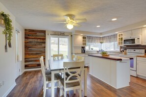 A modern kitchen with wooden flooring, white cabinetry, and a central island. - Sauna, Spa & Stargazing: Coudersport Home! (Coudersport)