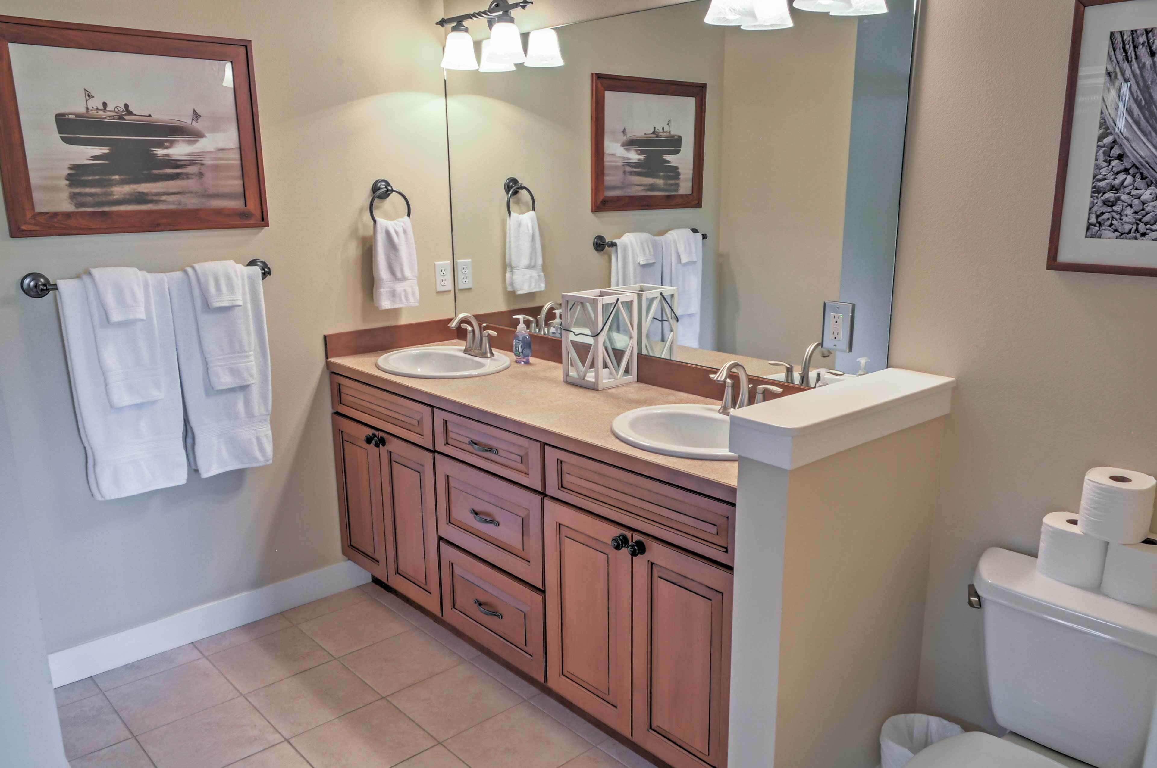 A bathroom with two sinks, a large mirror, and wooden cabinets.