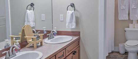 A bathroom with two sinks, a wooden vanity, a mirror, and a shower area.