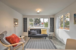 A modern living room with a sofa, a patterned rug, and a large window offering a view of the outside. - Sleek Cottage By Seattle's Top Sights, Lumen Field (Seattle)