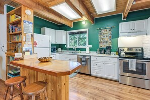 A kitchen with wooden beams, white cabinets, a stainless steel oven, and a wooden island with stools. - Cozy Ashford Home - 5 Mi to Rainier Nat'l Park! (Mineral)