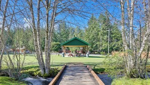 A wooden pathway leading to a green-roofed pavilion in a park with trees and picnic tables. - Cozy Ashford Home - 5 Mi to Rainier Nat'l Park! (Mineral)