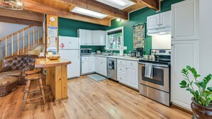 A kitchen with wooden floors, white cabinets, a bar area, and a staircase. - Cozy Ashford Home - 5 Mi to Rainier Nat'l Park! (Mineral)