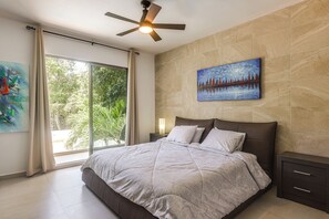 A bedroom with a bed, a ceiling fan, a painting, and a view of greenery through a window. - 1 Mi to Beach: Luxe Playa Del Carmen Home w/ Pool (Playa del Carmen)