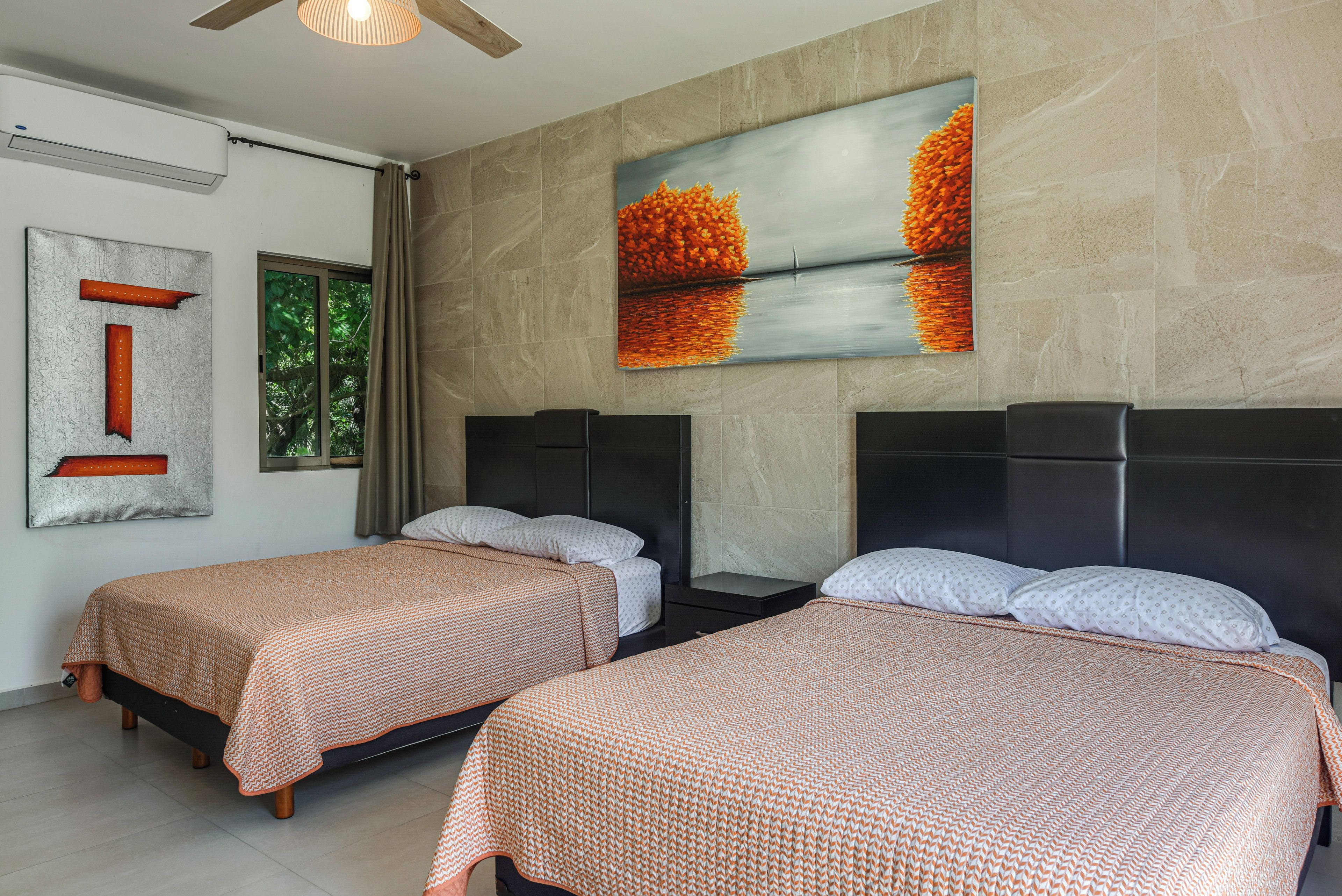 Una camera d'albergo con due letti, un quadro di grandi dimensioni e una finestra con tende.