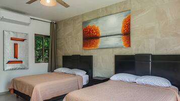 Una camera d'albergo con due letti, un quadro di grandi dimensioni e una finestra con tende.