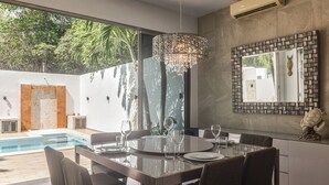 Un comedor moderno con una mesa de vidrio, sillas y una lámpara decorativa.