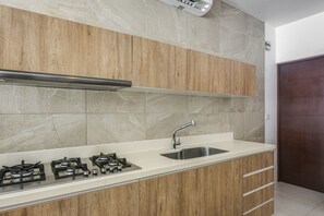 A modern kitchen with wooden cabinets, a stainless steel sink, and a gas stove. - 1 Mi to Beach: Luxe Playa Del Carmen Home w/ Pool (Playa del Carmen)