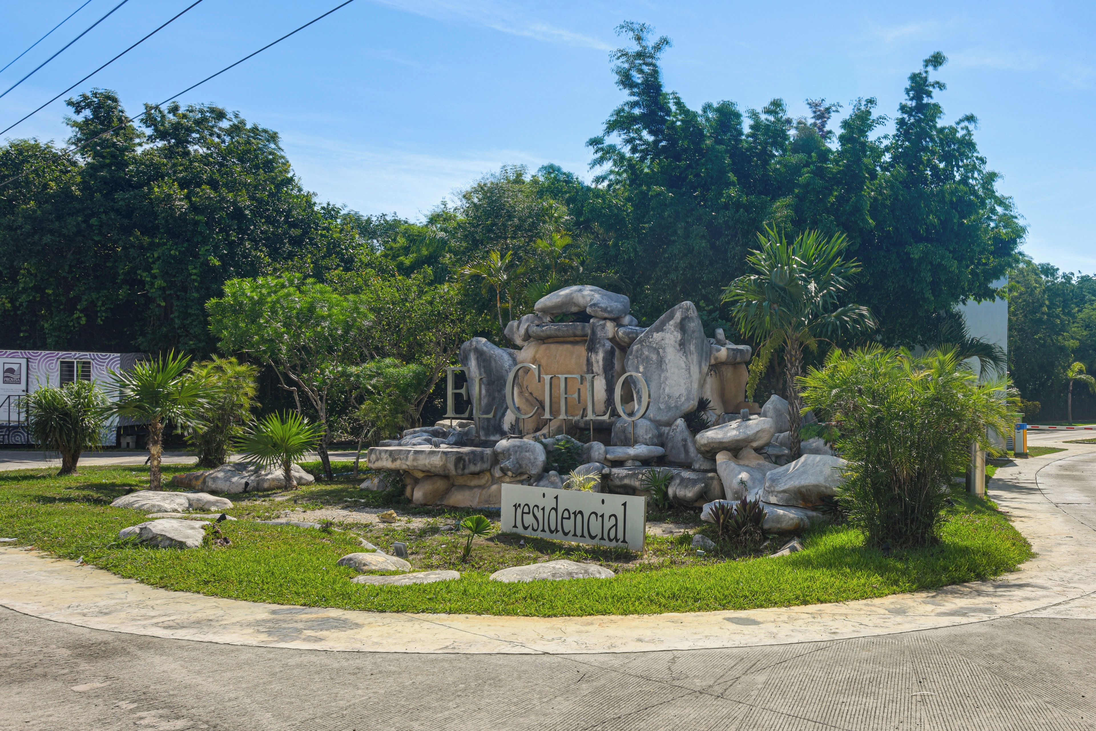 Un área residencial con una estructura de piedra, un letrero que dice 'residencial' y follaje circundante.