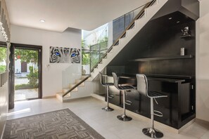 A modern interior with a staircase, a bar area, and a painting of a cat's eye. - 1 Mi to Beach: Luxe Playa Del Carmen Home w/ Pool (Playa del Carmen)
