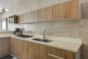 Eine moderne Küche mit Holzausstattung, einer Edelstahl-Spüle und einem Gasherd.