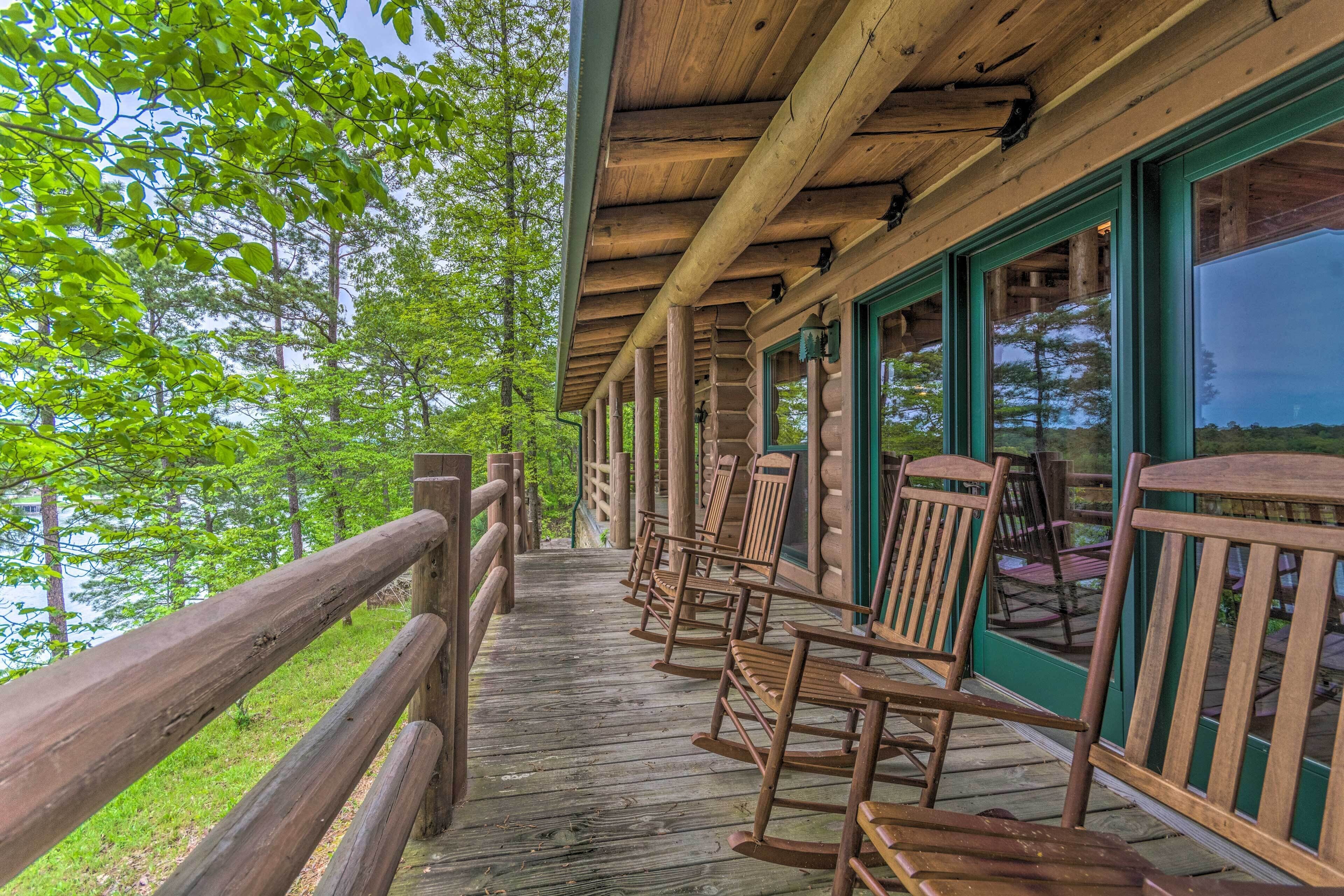 A wooden deck with rocking chairs and a view of the surrounding forest.