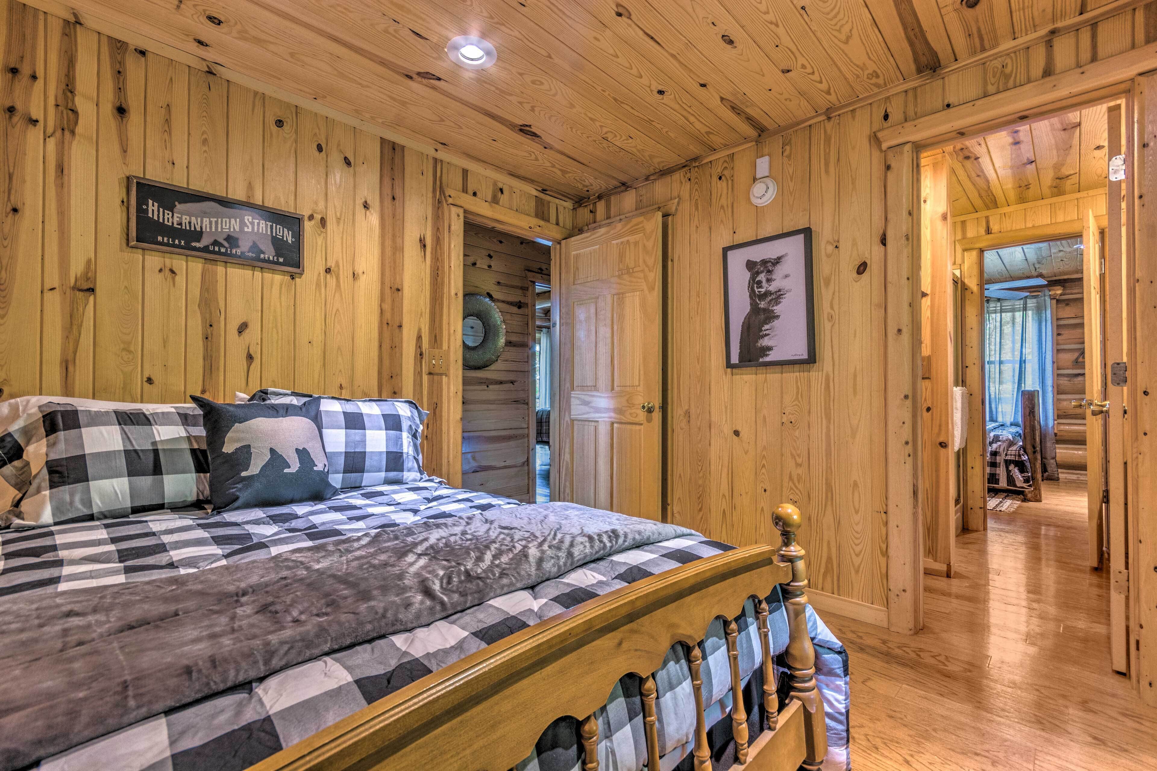 A wooden cabin interior with a bed, a sign reading "Hibernation Station," and a framed picture on the wall.