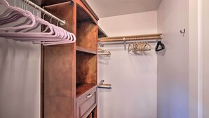 Un armario espacioso con estantes de madera, una barra para colgar ropa y una repisa para libros.