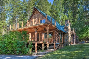 A log cabin with a stone chimney, wooden deck, and a staircase leading to a second level. - Alpine Adventures: Cozy Log Cabin w/ Deck & Views! (Alpine)