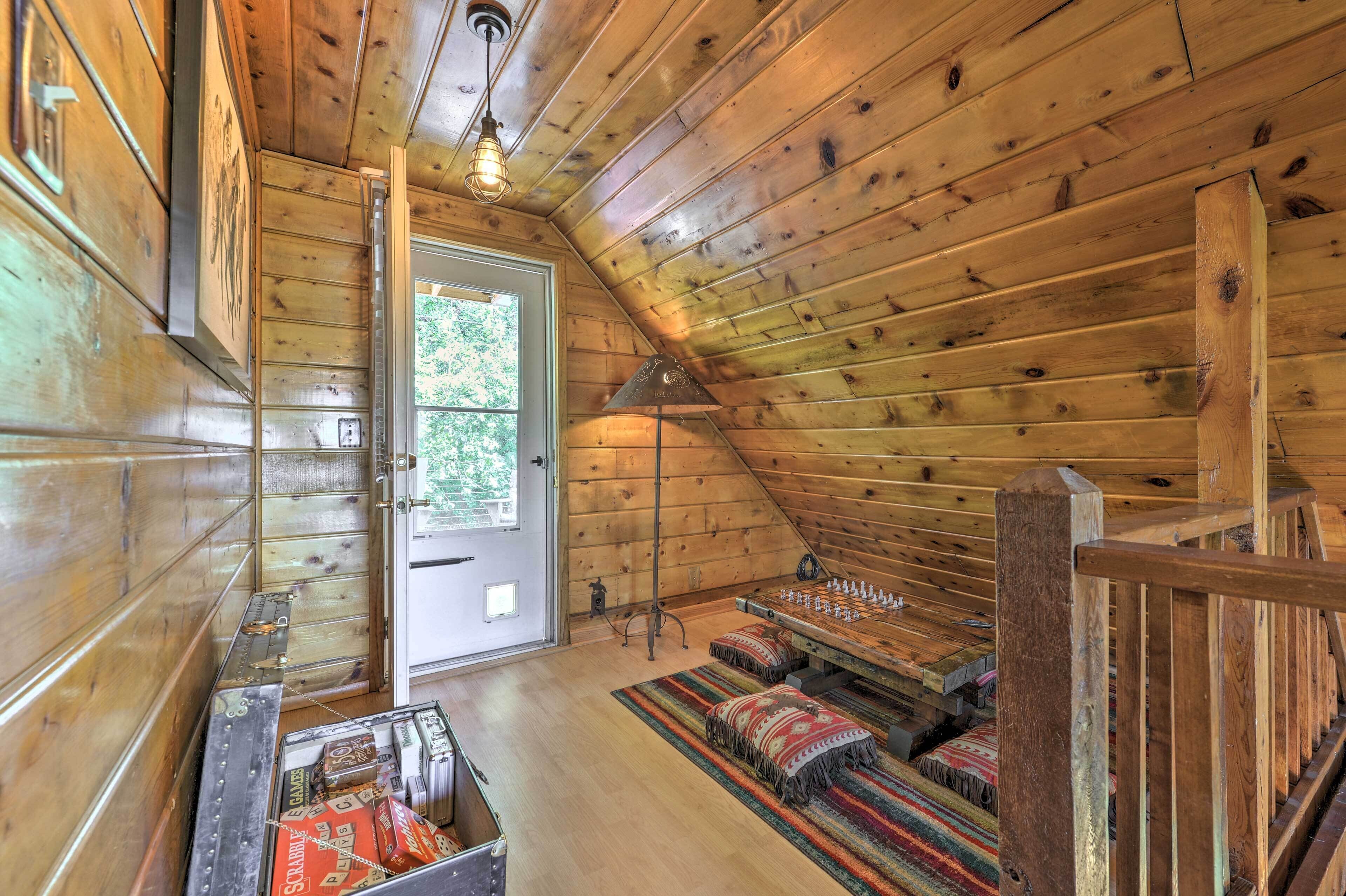 A cozy cabin interior with wooden walls, a door leading outside, a chessboard, and a small table with snacks.