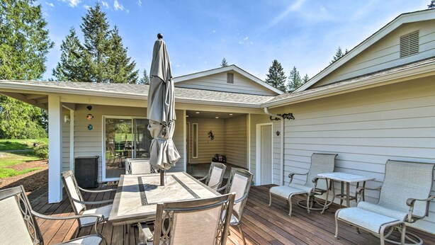 A covered patio with a table and chairs, a small table with a chair, and a covered area with a bench. - Spacious Family Home on Golf Course: Hike & Bike! (Bremerton)