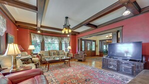 A spacious living room with a large red rug, leather sofa, and a television on a wooden cabinet. - Historic Auburn House on 37 Acres w/ Private Lake! (Kent)