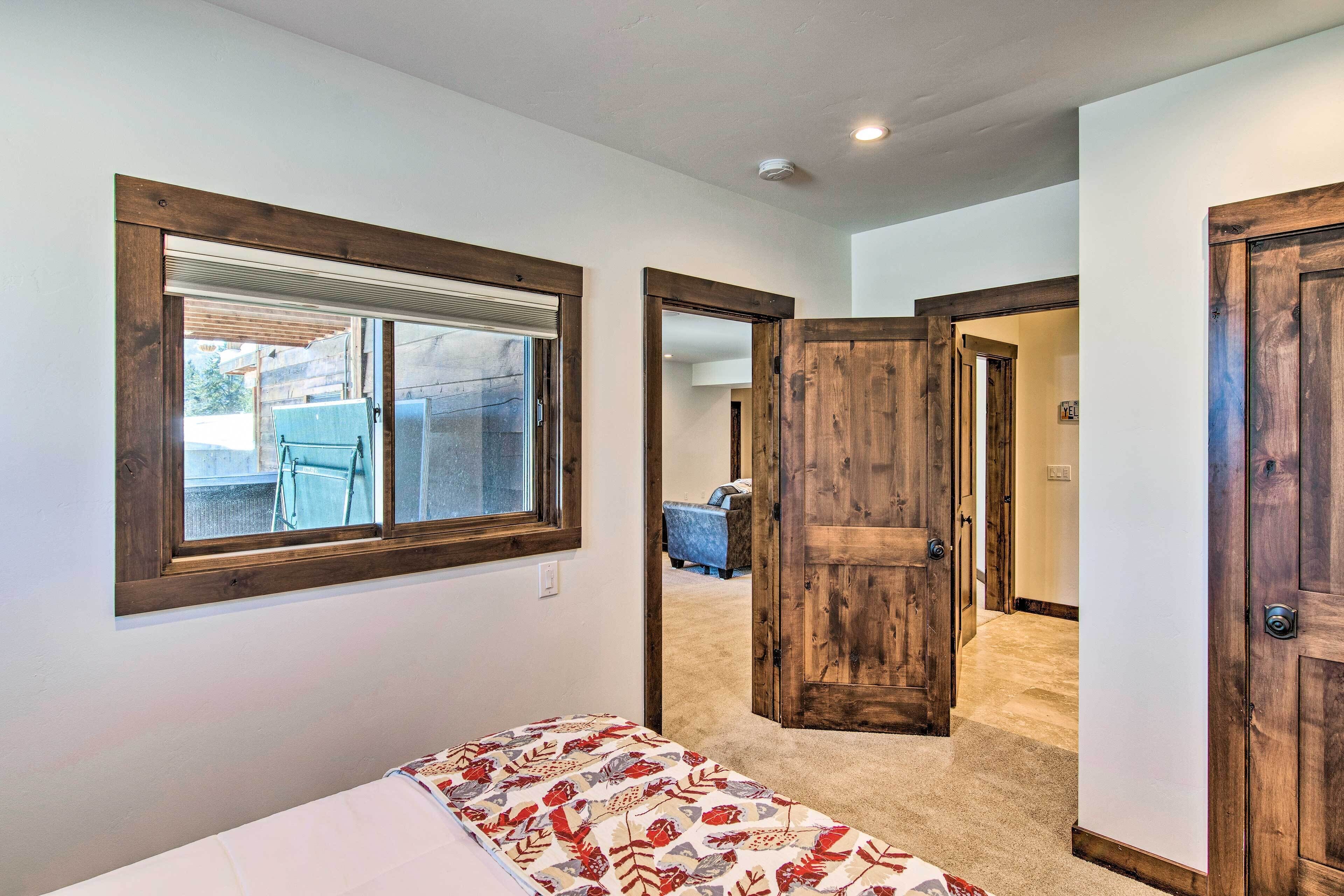 A bedroom with a bed, a window, and a door leading to another room.
