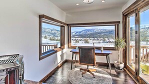 A corner room with a large window offering a mountain view, a wooden desk, a chair, and a potted plant. - Spacious Big Sky Cabin w/ Hot Tub & Grill! (Big Sky)