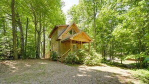 A wooden cabin with a porch and a gravel driveway surrounded by trees. - Private Hot Tub, Yard: Pet-friendly Whittier Cabin (Whittier)
