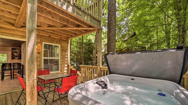 A wooden deck with a hot tub, outdoor seating, and a view of the forest. - Private Hot Tub, Yard: Pet-friendly Whittier Cabin (Whittier)
