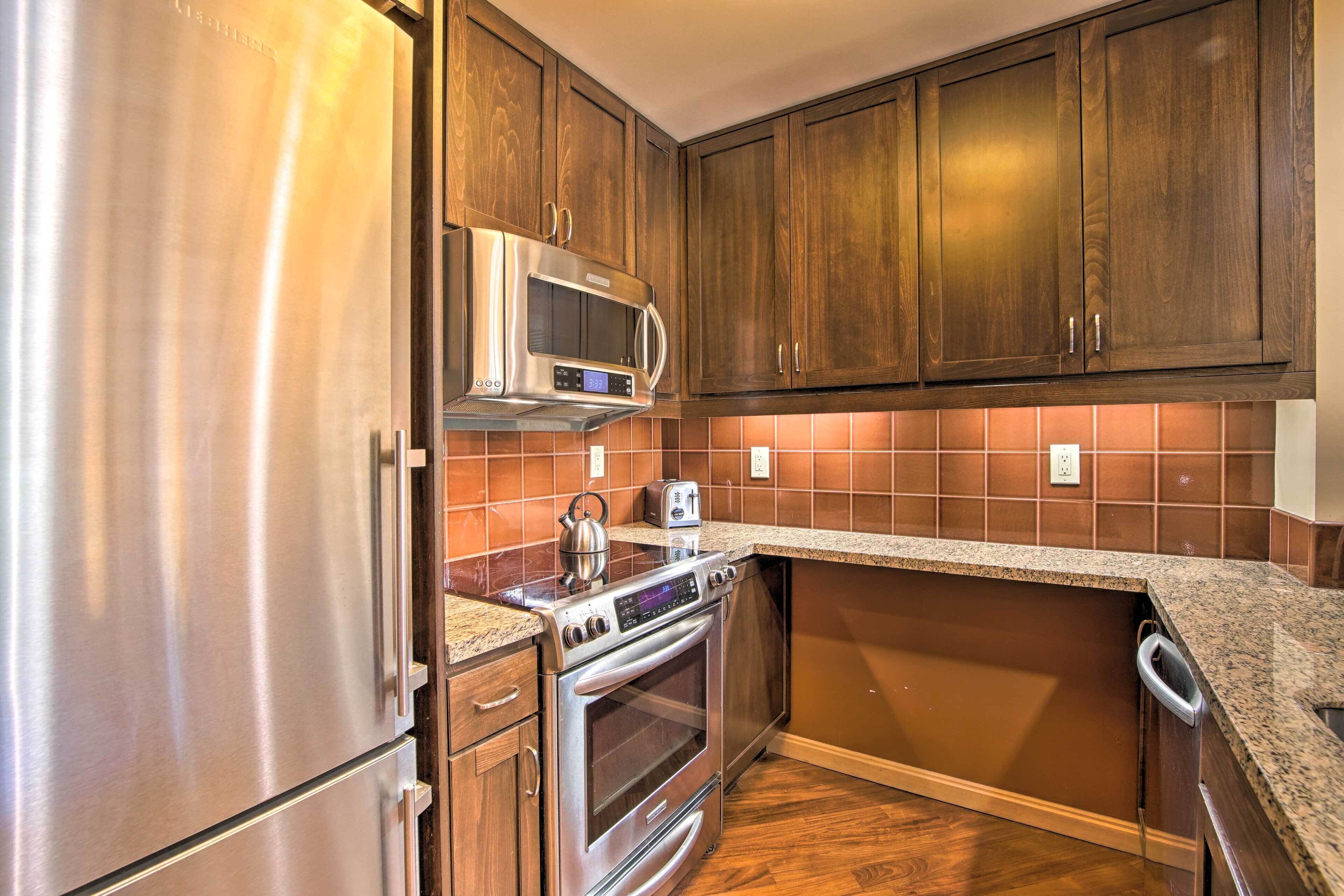 A kitchen with stainless steel appliances, wooden cabinets, and a tiled backsplash.