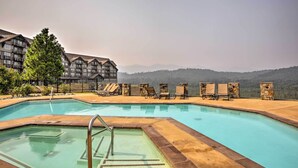 Ein Pool mit Liegestühlen und einer Steinmauer, umgeben von einem Gebäude mit Balkonen.