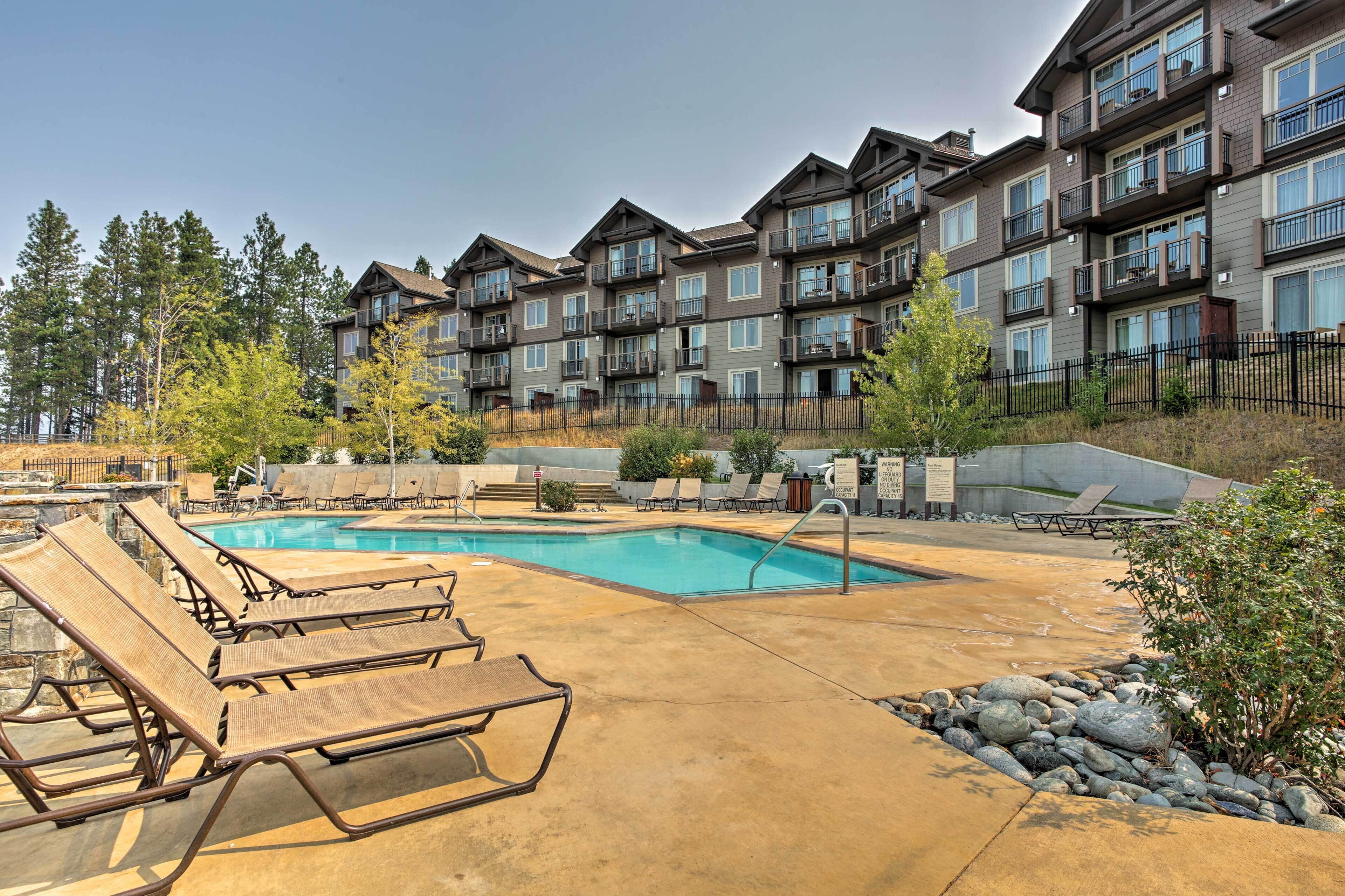 A pool area with lounge chairs, a swimming pool, and a multi-story building with balconies.