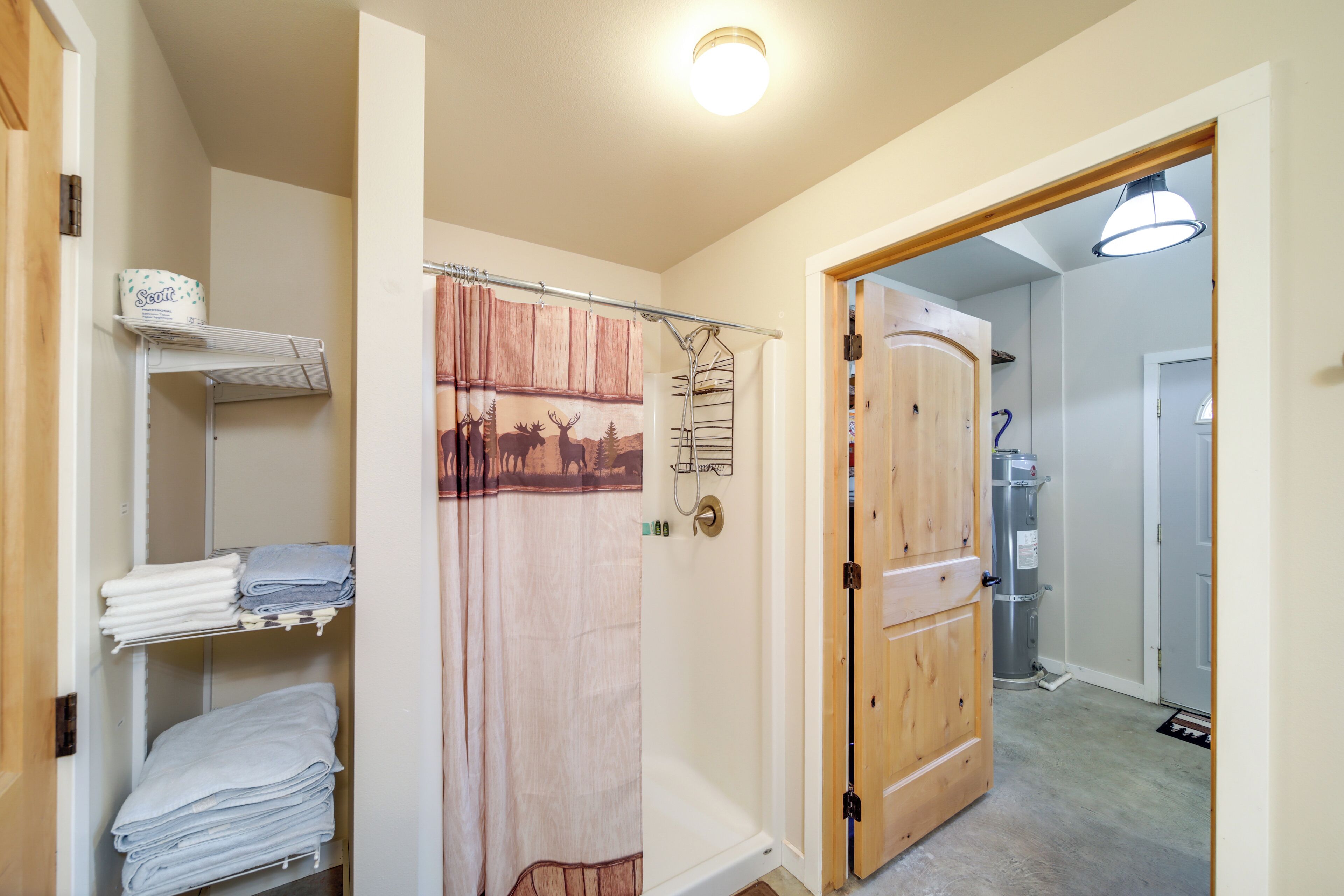 A bathroom with a shower curtain, a towel rack, and a wooden door.