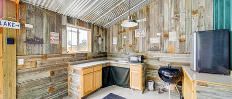 A rustic cabin with a wooden interior, a sink, a refrigerator, and a grill.