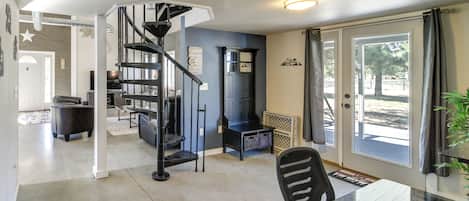 Eine moderne Küche mit einer schwarzen Wendeltreppe, einem Essbereich mit einem Glastisch und Blick durch eine Glastür.