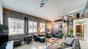 A spacious living area with a fireplace, leather furniture, and a staircase leading to an upper level.