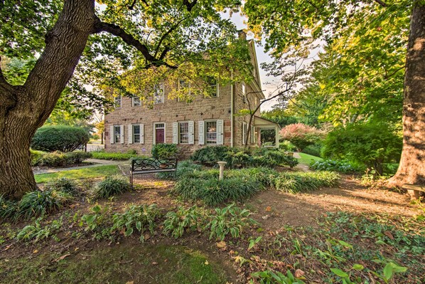 A stone building with a garden in front, surrounded by trees.