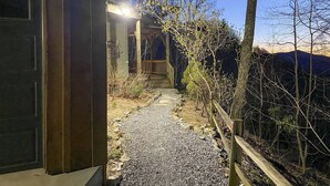 A gravel path leading to a wooden house with a porch. - Serene 'mountain Mist' Retreat w/ Deck & Hot Tub! (Maggie Valley)