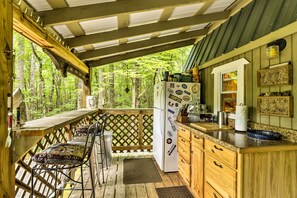 A rustic wooden cabin with a kitchen area featuring a refrigerator, bar stools, and a wooden counter. - 'lotsa Moose Lodge' Pisgah Forest Waterfall Cabin! (Burnsville)