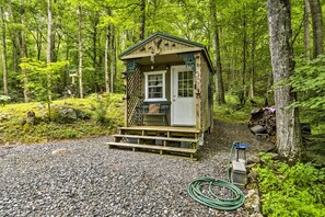 A small wooden cabin with a porch, surrounded by a forest.