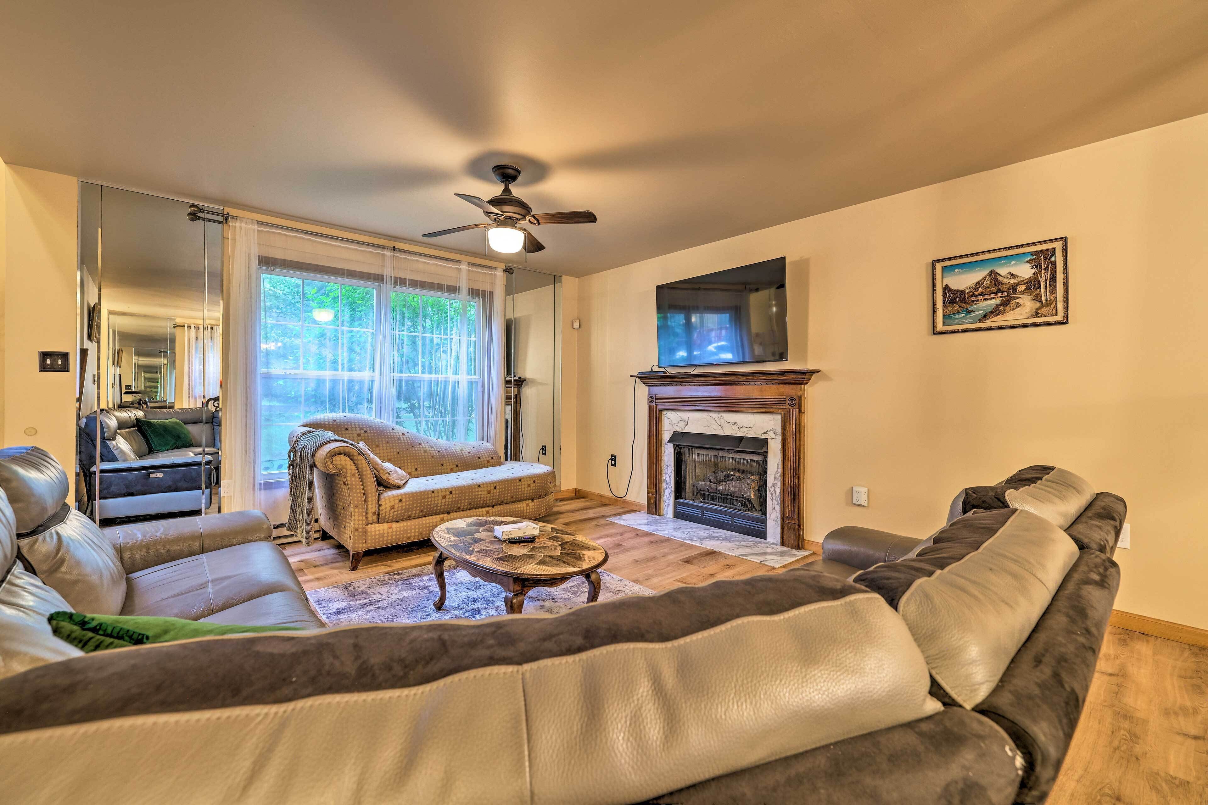 A living room with a fireplace, leather sofas, a coffee table, and a large window.