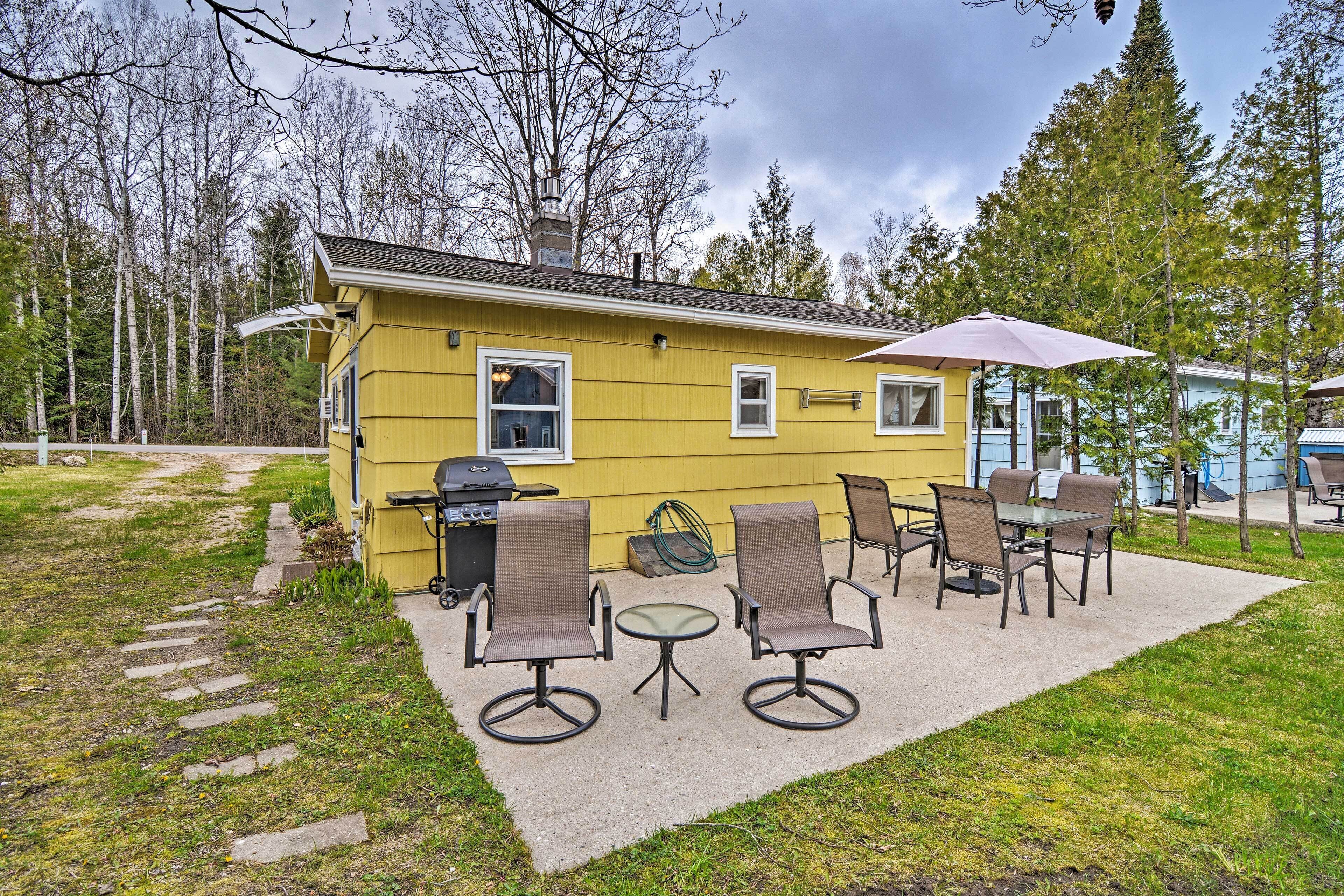 Ein gelbes Haus mit Terrasse, Sitzgelegenheiten im Freien und Grill.