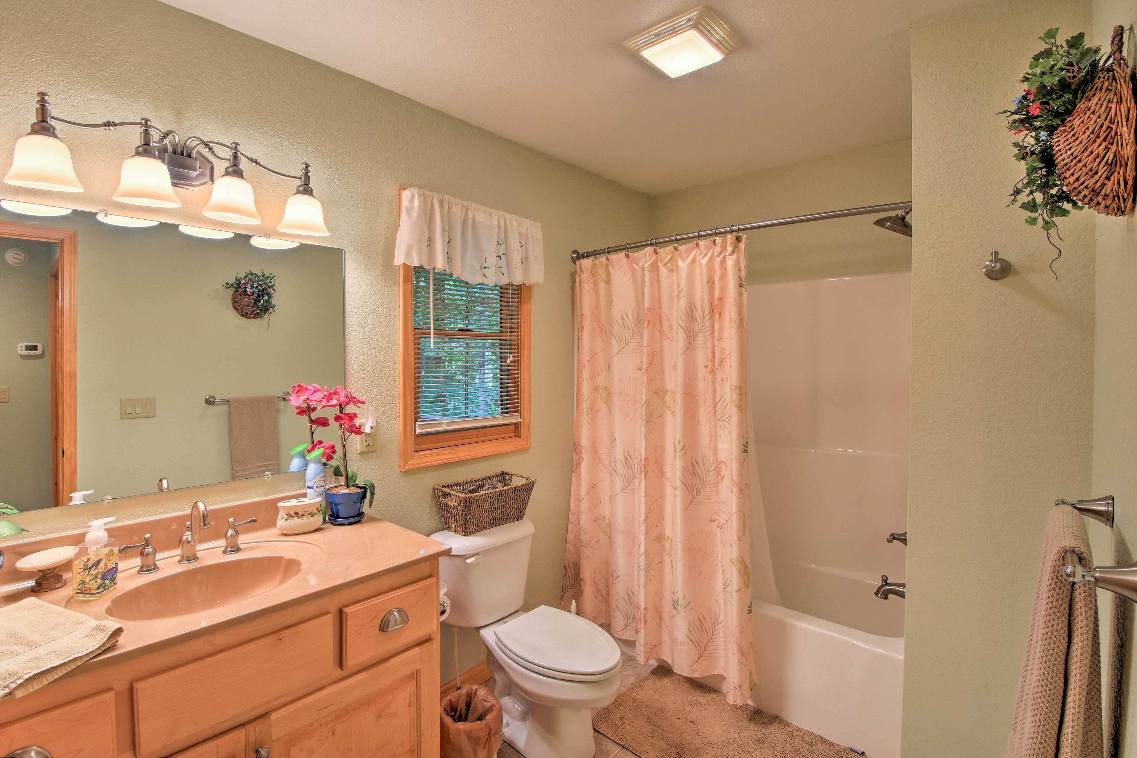 A bathroom with a sink, mirror, toilet, and bathtub.